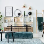 Modern living room with white shelving unit, wall art, plants, and a black coffee table centerpiece.
