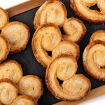Palmiers pastries arranged on a dark serving board, golden and flaky.