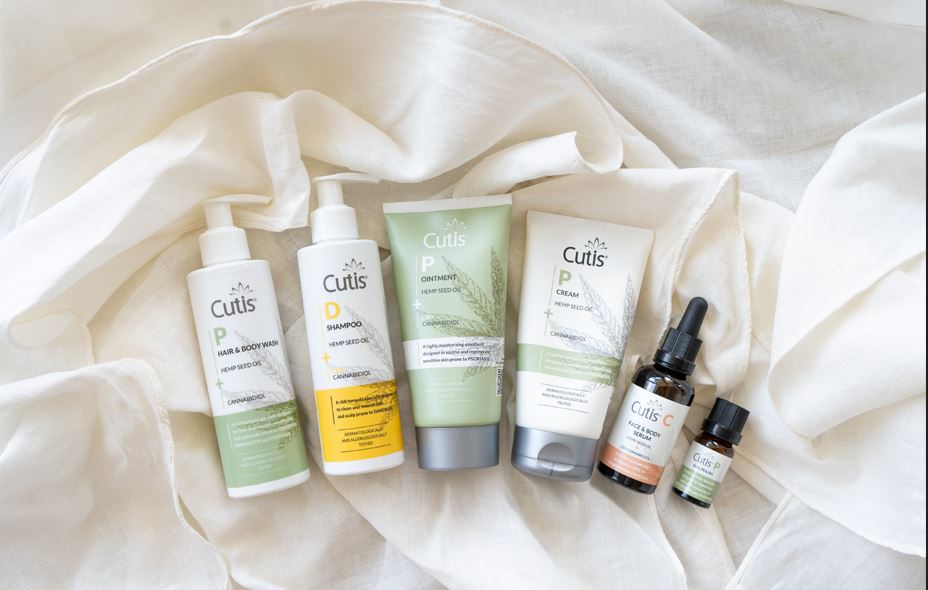 Assorted Cutis hemp seed oil hair and skincare products arranged on white fabric.