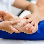 Physical therapist holds and massages a patient's foot during a therapy session.