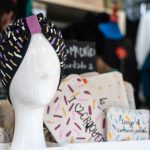 Mannequin head wearing a black turban with multicolored sprinkles pattern and purple accent, in a shop display.